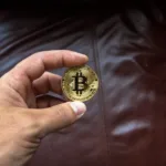 round gold colored and black coin on person s hand