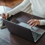 crop faceless female entrepreneur doing multitasking work on different devices