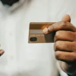 person holding brown credit card and cellphone