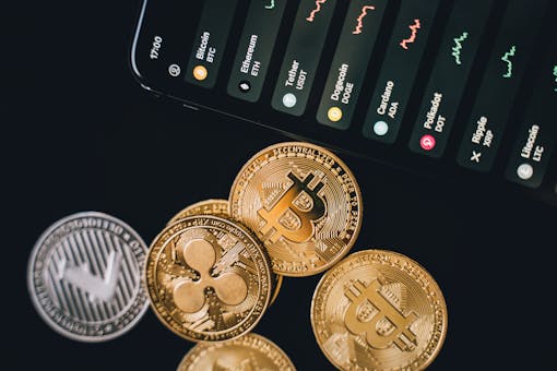 Close-up view of various cryptocurrency coins with a digital market display in the background.
