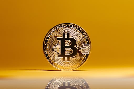 Golden Bitcoin coin showcased against a vibrant yellow background, symbolizing digital currency.