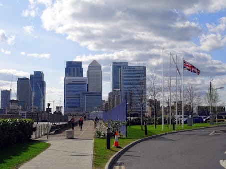 A view of the Canary Wharf skyscrapers in London, UK with a Union Jack flag in the foreground.