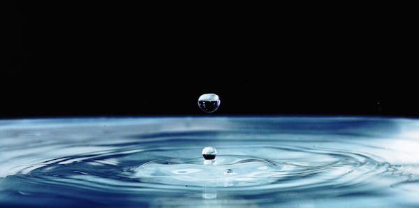 Captivating macro shot of a water droplet impacting a calm surface, showcasing detail and movement.