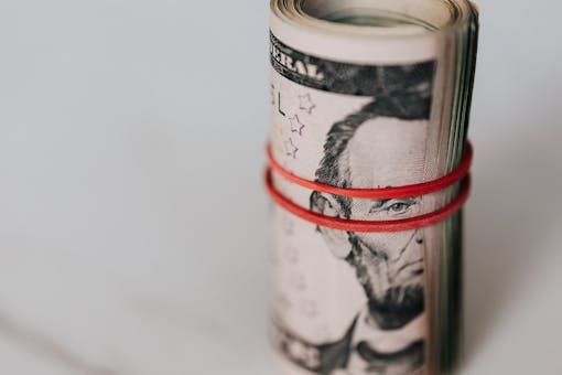 Close-up of a roll of US dollars wrapped with a red rubber band focusing on financial abundance.