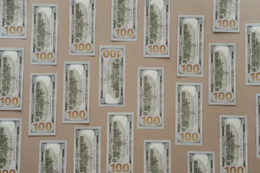 Flatlay of hundred dollar bills arranged on a surface representing wealth and finance.