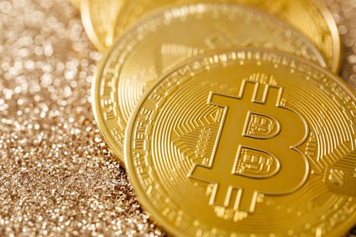 Golden Bitcoin coins on a shimmering glitter surface, symbolizing digital currency and financial innovation.