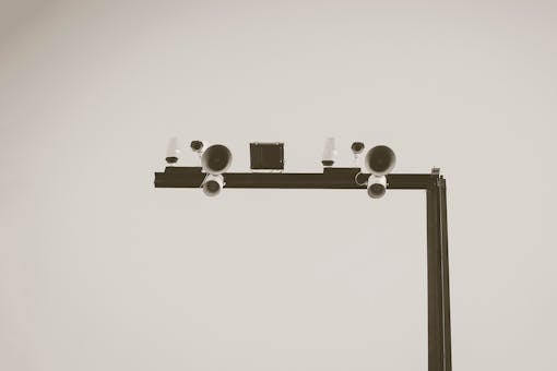 Monochrome image of CCTV cameras and speakers on an outdoor metal frame in Barcelona.