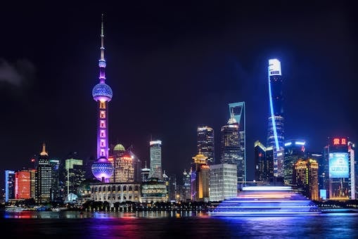 Stunning night view of Shanghai skyline with illuminated skyscrapers and the Oriental Pearl Tower reflecting in the water.
