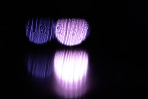 Blurred abstract capture of purple light reflections against a dark background, creating a mysterious ambiance.