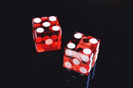 Close-up of two red dice on black surface, symbolizing chance and luck.