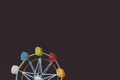 Colorful Ferris wheel lit up at night, providing a vibrant contrast against the dark sky.